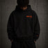 Zwarte oversized hoodie met rode borstprint, capuchon en logomotief op de mouw