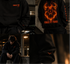 Zwarte hoodie close-up met vlammenprint, rode tekst en logomotief op borst en mouw