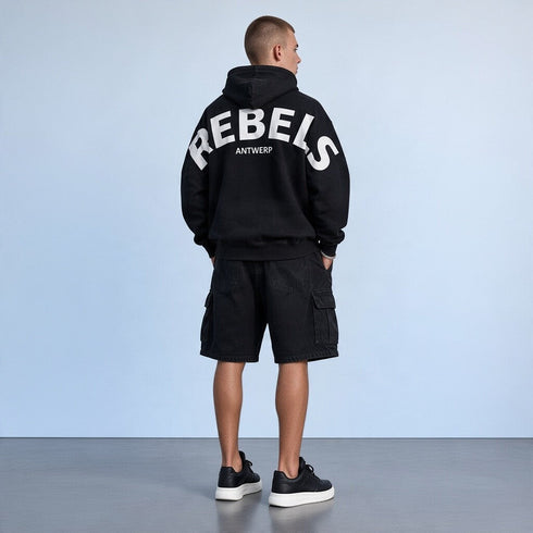 Zwarte oversized hoodie met capuchon en gebogen witte tekst op de rug.