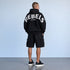 Zwarte oversized hoodie met capuchon en gebogen witte tekst op de rug.