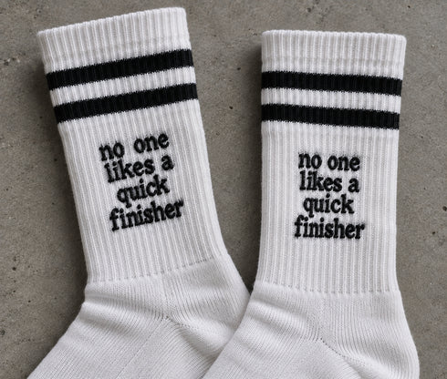 Witte sportkousen met zwarte strepen en tekst 'no one likes a quick finisher'