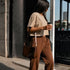 Zandkleurig cropped T-shirt met korte mouwen en borstlogo; bruine sweatpants met elastische taille.