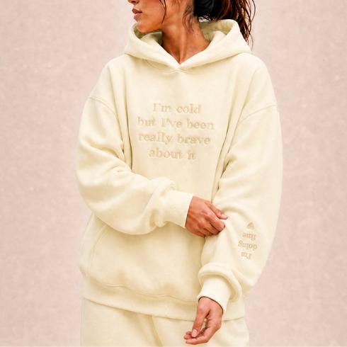 Roomwitte oversized hoodie met capuchon en geborduurde tekst op de borst