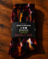 Tie-dye sok zwart-bordeaux-oranje met Swirly Sox etiket 'MADE IN BELGIUM'.