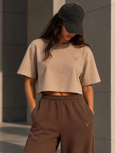 Zandkleurig boxy cropped T-shirt met klein borstlogo; bruine sweatpants met elastische taille.