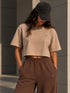 Zandkleurig boxy cropped T-shirt met klein borstlogo; bruine sweatpants met elastische taille.