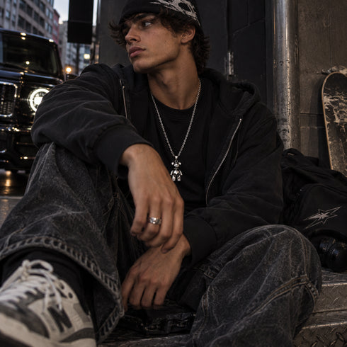 man wearing long silver bear necklace
